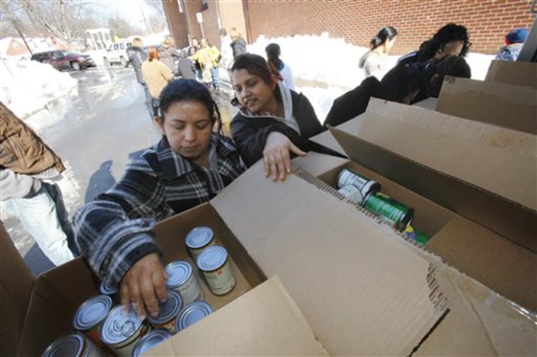 Mercedes Rodas, left, chooses cans of food that were being provided Friday to people whose children are usually in the school lunch program at Rolling Terrace Elementary School in Takoma Park, Md.